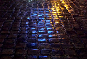 Beauty of Imperfection : wet cobblestone pavement reflecting street lights in Medieval town of St Valery sur Somme, France.