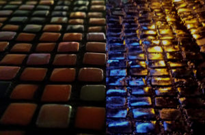 Beauty of Imperfection : Light reflections on glass Opus pixellatum mosaic and wet Cobblestone street pavement.